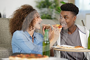 smiling young couple with pizza on sofa at home