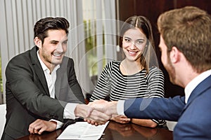 Smiling young couple shaking hands with an insurance agent