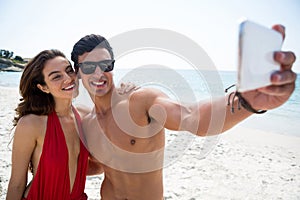 Smiling young couple taking selfie at beach