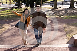 Smiling young couple talking while walking through a public park. Friendship and human relations concept