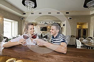 Smiling young couple toasting wine glasses at restaurant counter