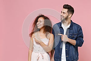 Smiling young couple two friends european guy african american girl in casual clothes isolated on pastel pink background