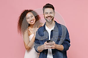 Smiling young couple two friends european guy african american girl in casual clothes posing isolated on pastel pink
