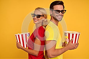 Smiling young couple two friends guy girl in 3d glasses posing  on yellow background. People in cinema lifestyle concept.