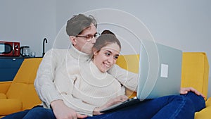 a smiling young couple using laptop at home indoor