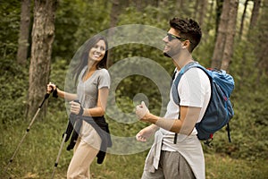 Smiling young couple walking with backpacks in the forest