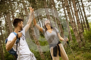 Smiling young couple walking with backpacks in the forest