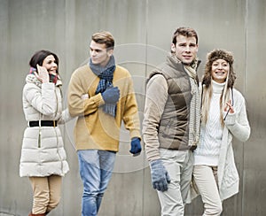 Smiling young couples walking against wall