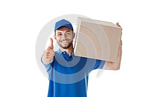 Smiling young delivery man with parcel box showing thumbs up