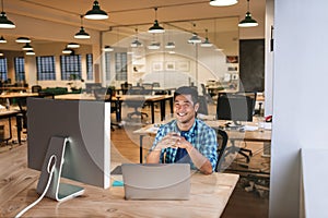 Smiling young designer working at his desk in an office