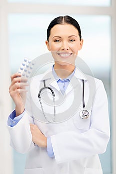 Smiling young doctor with pills and sthethoscope photo