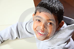 Smiling young ethnic school boy wearing grey hoodi photo