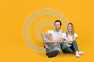 Smiling young european female and female sitting on floor and looking at camera