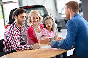 Smiling young family with car dealer photo