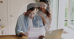 Smiling young family couple reading paper correspondence letter.