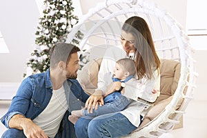 Smiling young family enjoy spending time with their cute baby girl during Christmas
