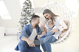 Smiling young family enjoy spending time with their cute baby girl during Christmas