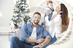 Smiling young family enjoy spending time with their cute baby girl during Christmas