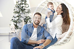 Smiling young family enjoy spending time with their cute baby girl during Christmas