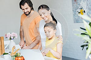 smiling young family using laptop together