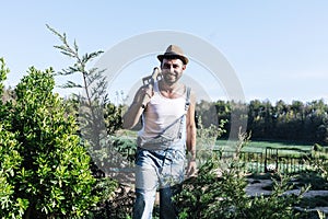 Smiling young farmer man standing in the garden while looking away