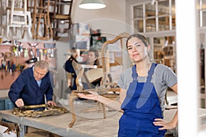 Smiling young female carpenter showing around local furniture workshop