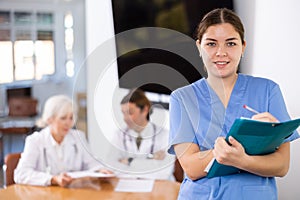 Smiling young female doctor filling out medical form