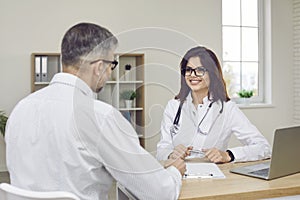 Smiling young female doctor giving a medical consultation to a mature male patient