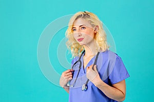 Smiling young female doctor or nurse wearing blue scrubs and stethoscope