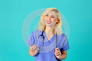 Smiling young female doctor or nurse wearing blue scrubs and stethoscope looking up