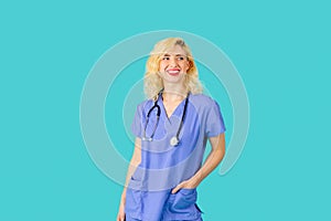 Smiling young female doctor or nurse wearing blue scrubs,  in studio