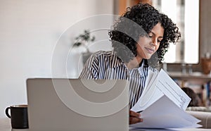 Smiling young female entrepreneur going over paperwork at home photo