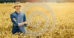 Smiling young female farmer standing with arms crossed in wheat cereal field. copy space