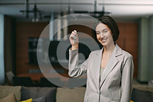 Smiling young female homeowner showing keys of modern flat, happy renter of apartment or real estate agent hold home key