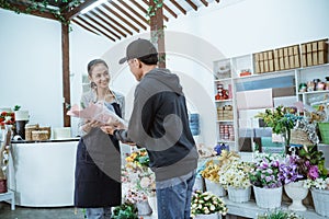 smiling young female shopkeeper wearing a apron. servicing male flannel flower buyers