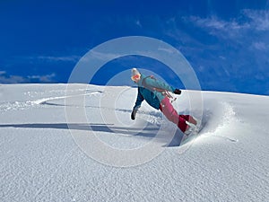 Smiling young female snowboarder rides the ungroomed slope on a sunny winter day photo