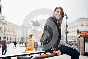 Smiling young female traveler enjoying at Sol square in the center of Madrid, Spain. Woman tourist holding a map near metro