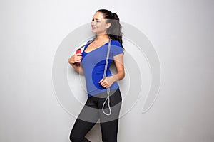 Smiling young fit woman standing with jump rope