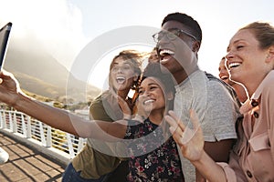 Smiling Young Friends Posing For Selfie On Outdoor Footbridge Together