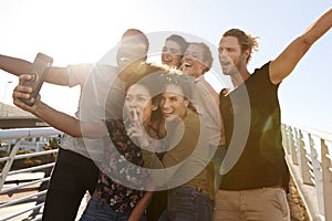 Smiling Young Friends Posing For Selfie On Outdoor Footbridge Together