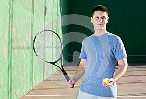 Smiling young frontenis player standing on open-air fronton court