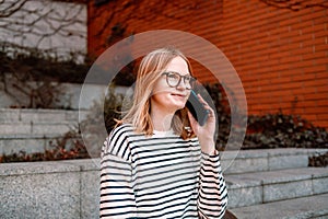 Smiling young girl in casual clothes using mobile phone