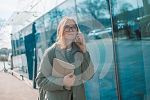 Smiling young girl in casual clothes using mobile phone