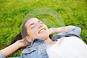 Smiling young girl with closed eyes lying on grass