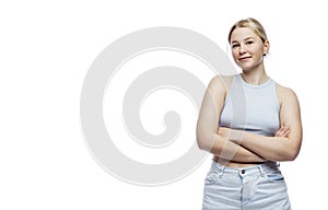 Smiling young girl. A cute blonde teenager in a blue top and jeans stands with her arms crossed over her chest. Isolated on a