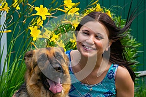 Smiling young girl with faithful friend on the background of flowers