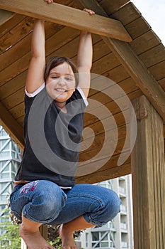 Smiling Young Girl Hanging on Wooden Structure
