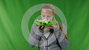 Smiling young girl holding a white water lily at face.