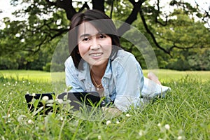 A smiling young girl with laptop outdoors