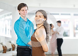 Smiling young girl practicing passionate samba with guy in dance class